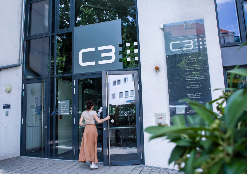 Eingang ins C3, eine junge Frau öffnet die Tür und geht hinein