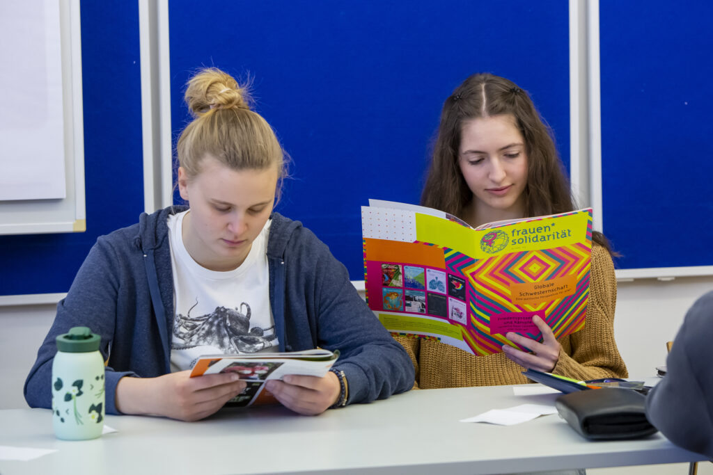 zwei Workshop Teilnehmer*innen, die die frauen*solidarität lesen.