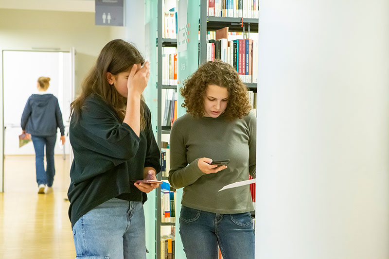 Besucher_innen in der Bibliothek arbeiten am Smartphone